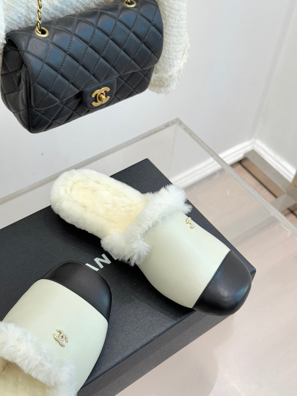 Chanel women's fur slides angled view, cream strap with black band, gold logo