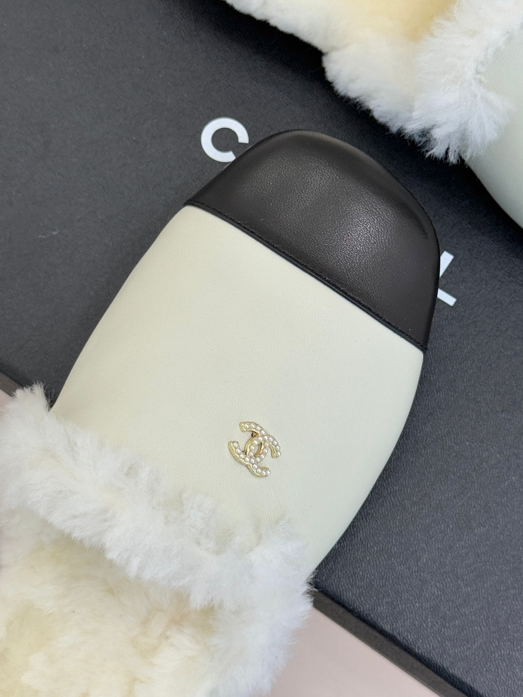 Chanel women's fur slide close-up, cream panel, black strap band, gold emblem