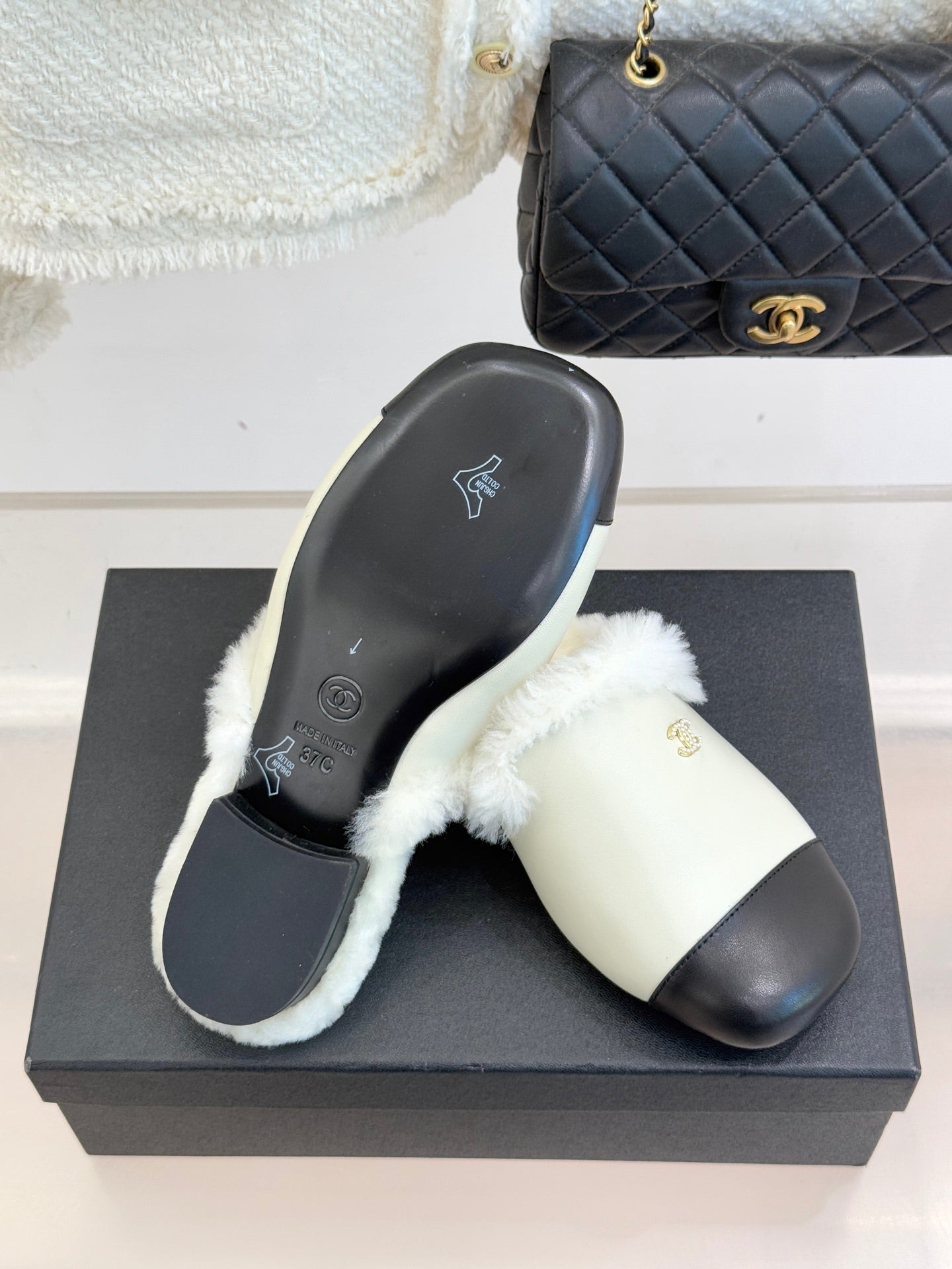 Chanel women's slides on black box, cream fur strap, black outsole with icons