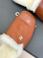 Close-up brown leather mule slipper with white shearling edge and gold Chanel logo