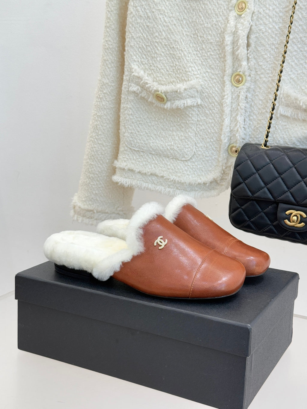 Brown leather mule slippers with white shearling trim and Chanel logo detail