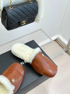 Brown leather mule slippers with white shearling band and gold Chanel emblem