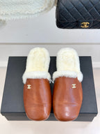 Brown leather mule slippers with white shearling uppers and gold Chanel emblem