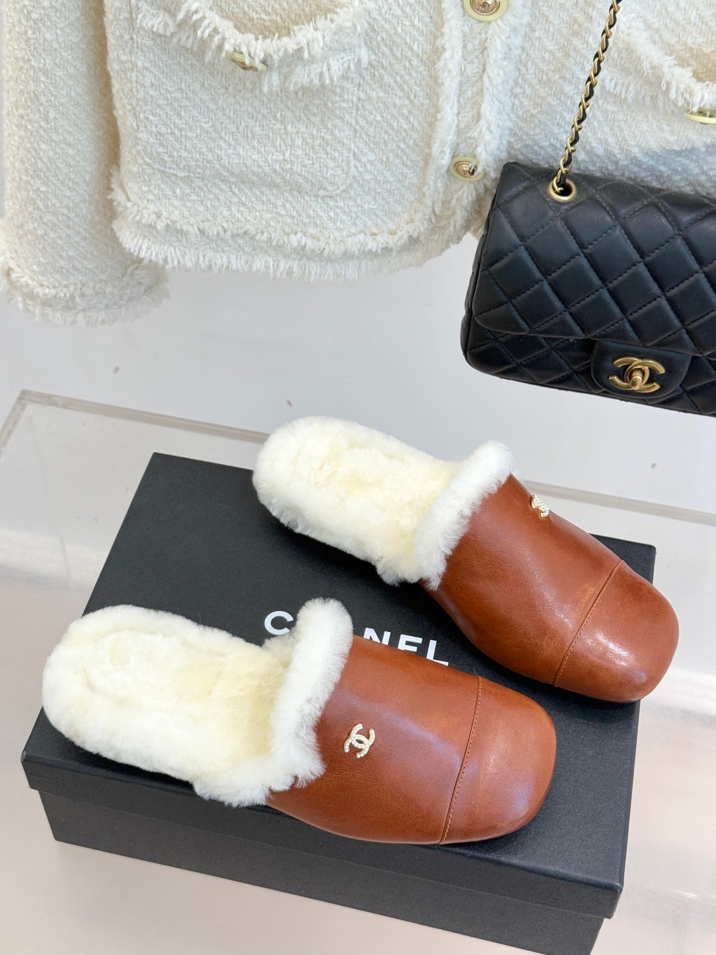 Brown leather mule slippers with white shearling top and small Chanel logo