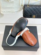 Brown leather mule slipper with white shearling trim and Chanel logo on side