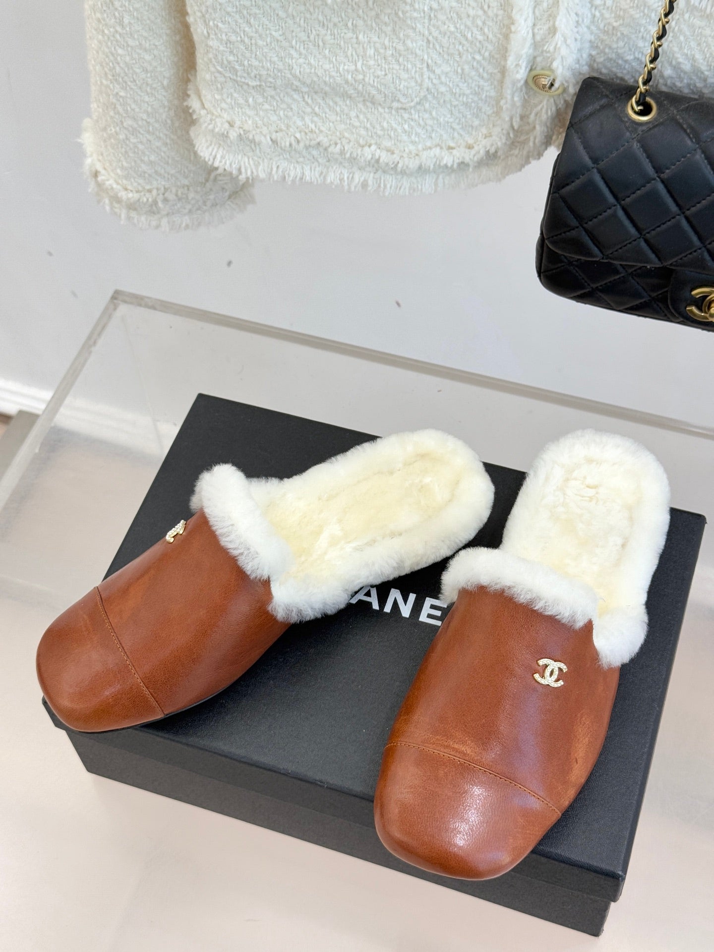 Pair of brown leather mule slippers with white faux fur strap and Chanel logo