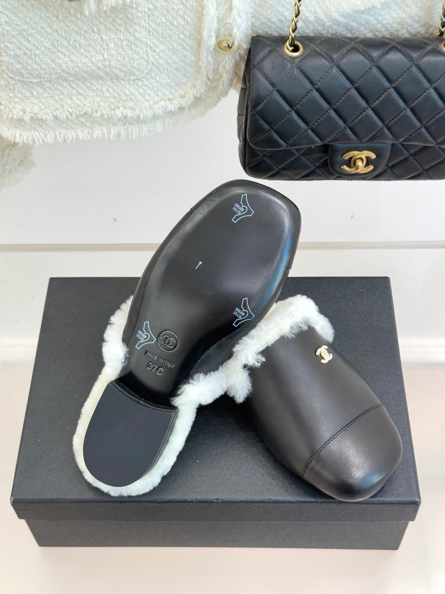 Black leather mule pair with white shearling trim and visible sole embossing