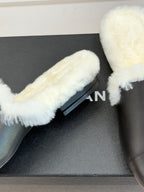 Close-up of black leather mule with white shearling strap and partial logo print