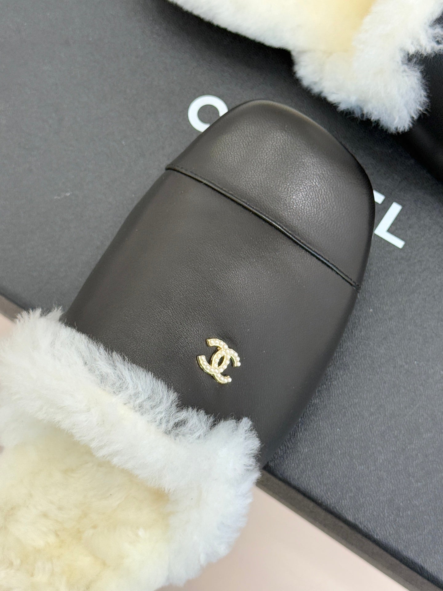 Black leather mule with white fur trim and small gold logo on side