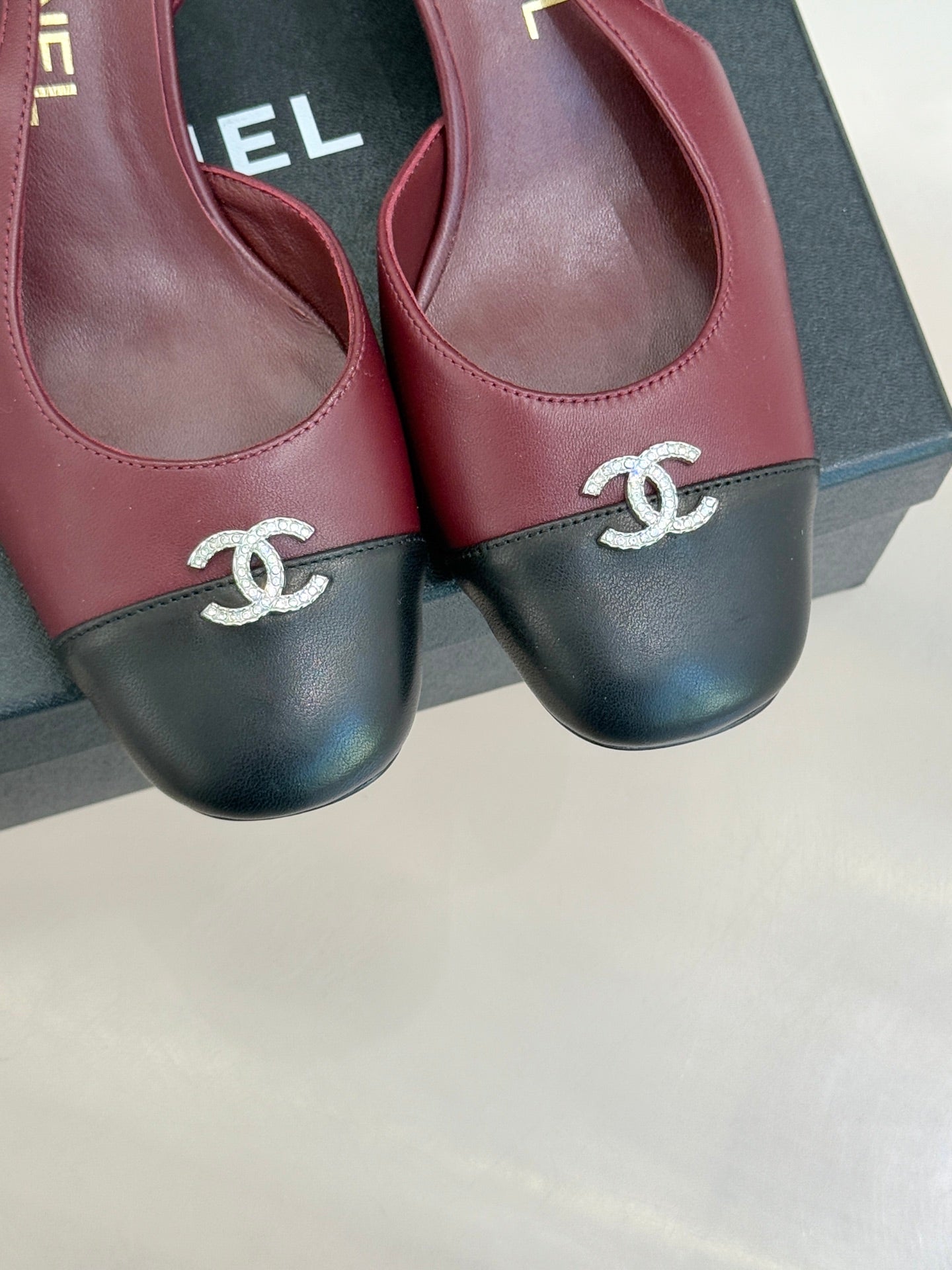 Chanel ladies pumps close-up, CC logo on burgundy-and-black toe band