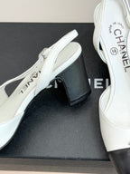 Women's two-tone mules close-up, white leather upper with dark block heel and insole text