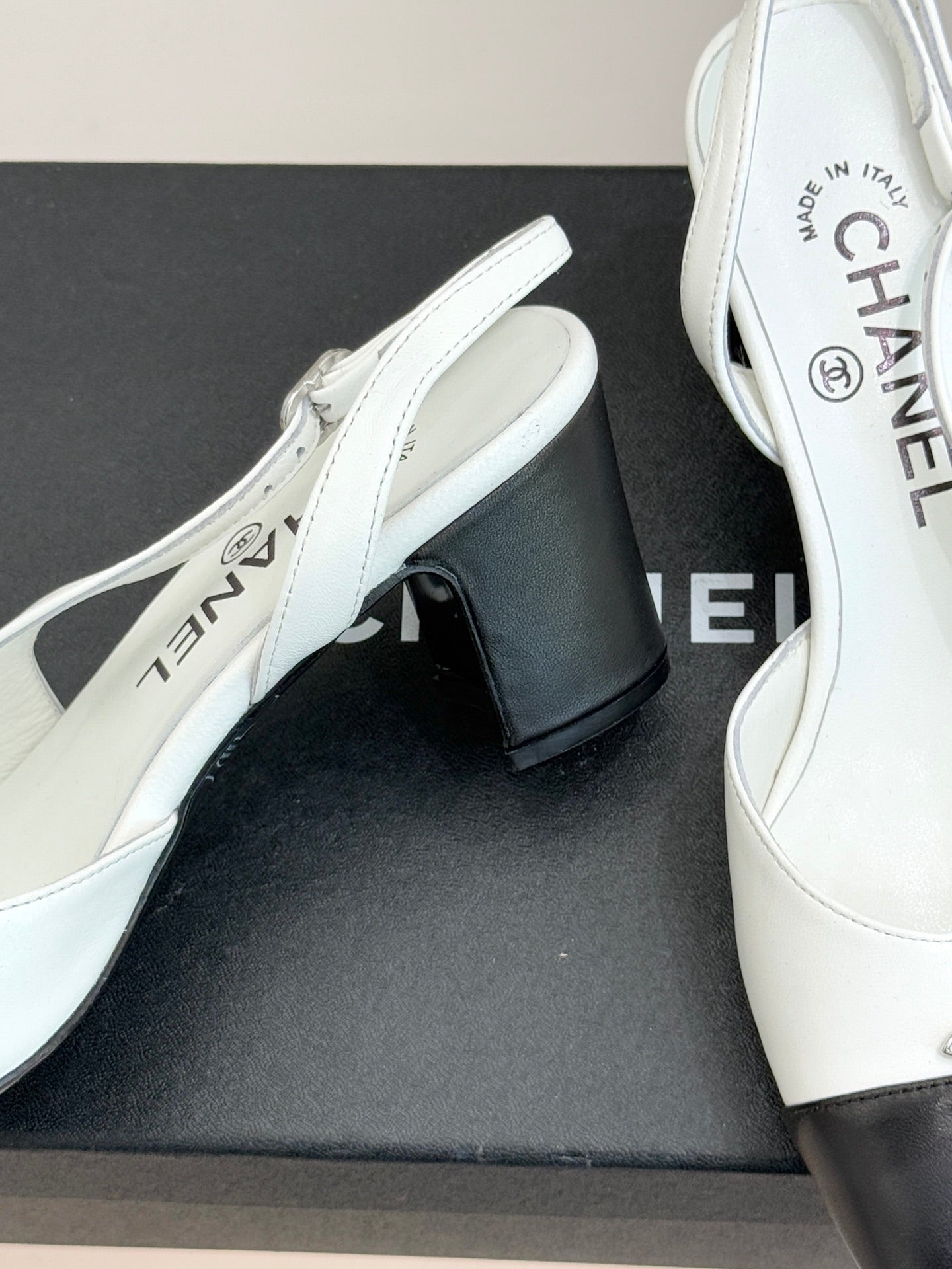 Women's two-tone mules close-up, white leather upper with dark block heel and insole text