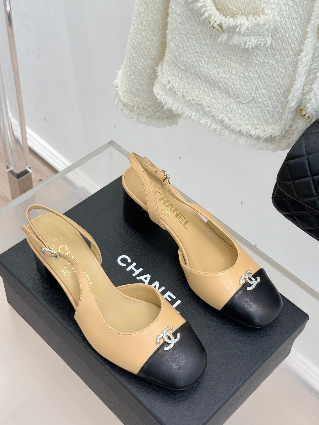 Women's Chanel two-tone slingback heels with black toe caps and CC logo, side view.