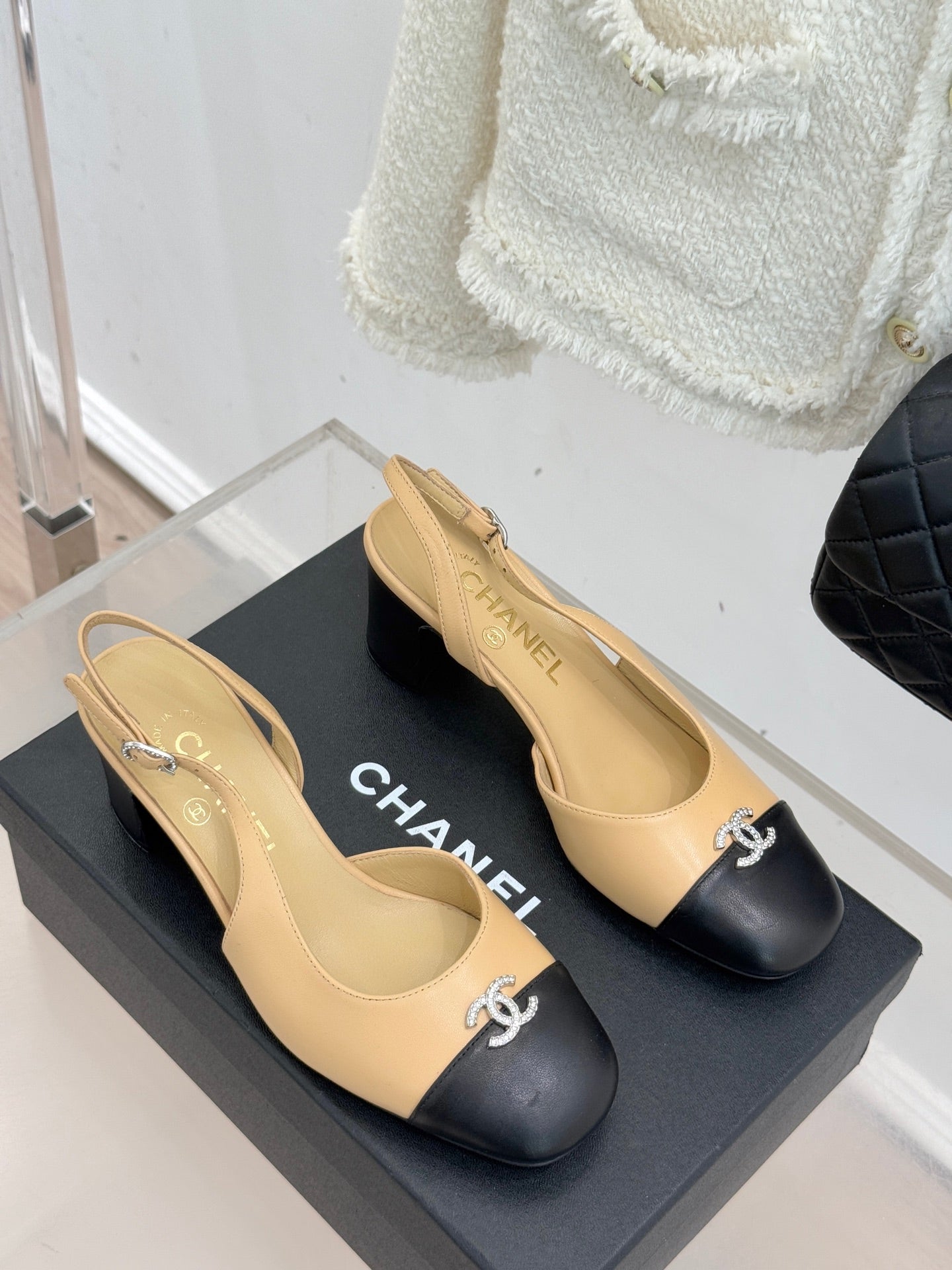 Women's Chanel two-tone slingback heels with black toe caps and CC logo, side view.