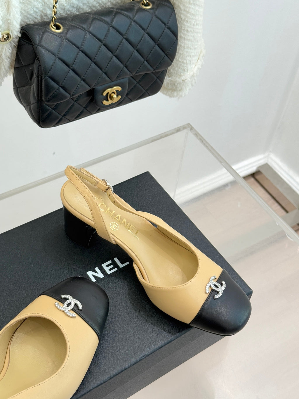 Women's Chanel two-tone slingback heels with black toe caps and CC emblem, angled view.