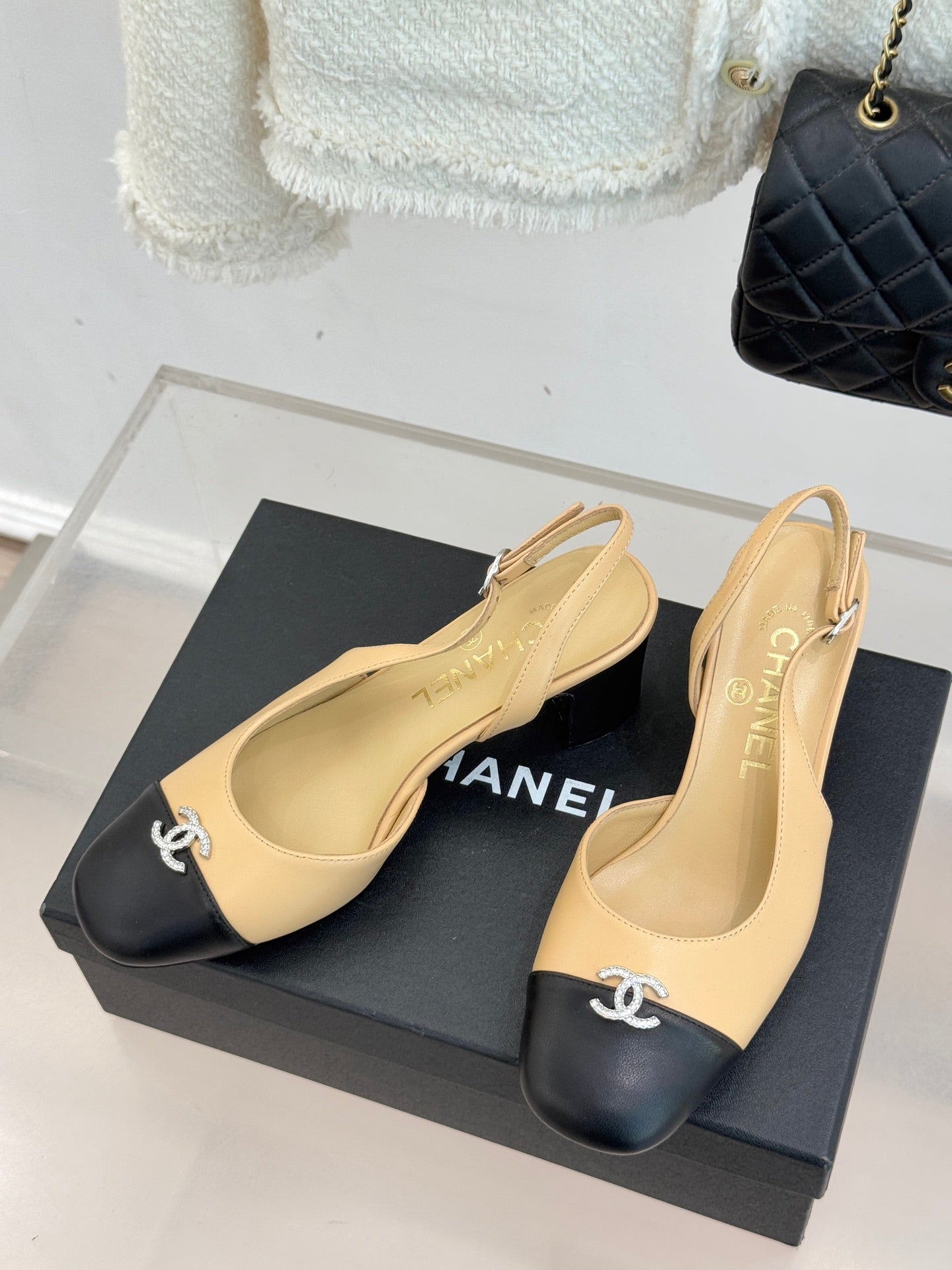 Women's Chanel slingback heels with beige uppers and black toe caps, pair on display.