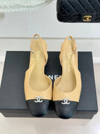 Women's Chanel slingback heels with beige uppers, black toe caps, CC emblem at front.