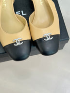 Women's Chanel slingback heels close-up, beige uppers, black toe caps, rhinestone CC.