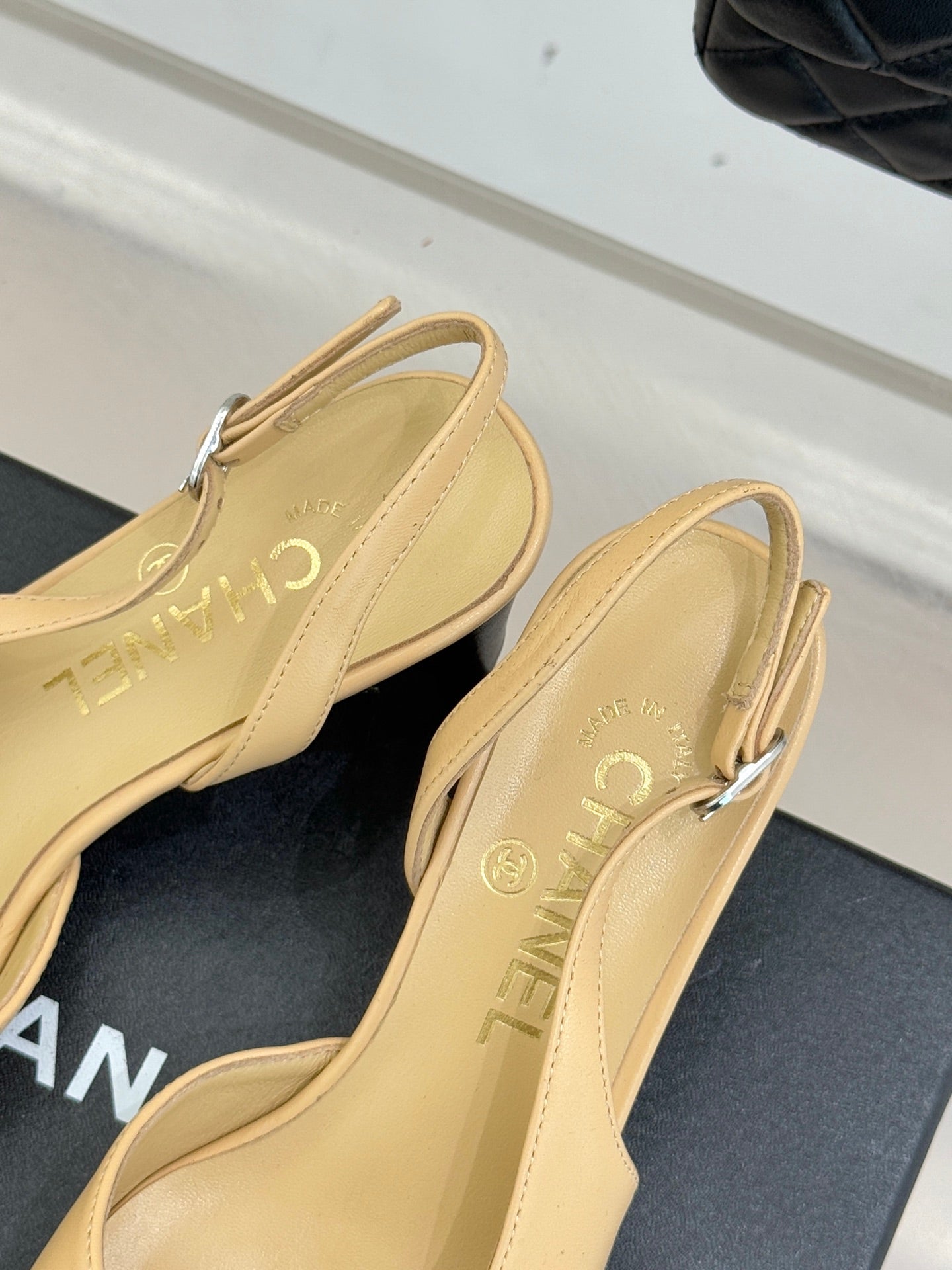 Women's Chanel slingback heels heel view, beige uppers with black toe caps, front strap.