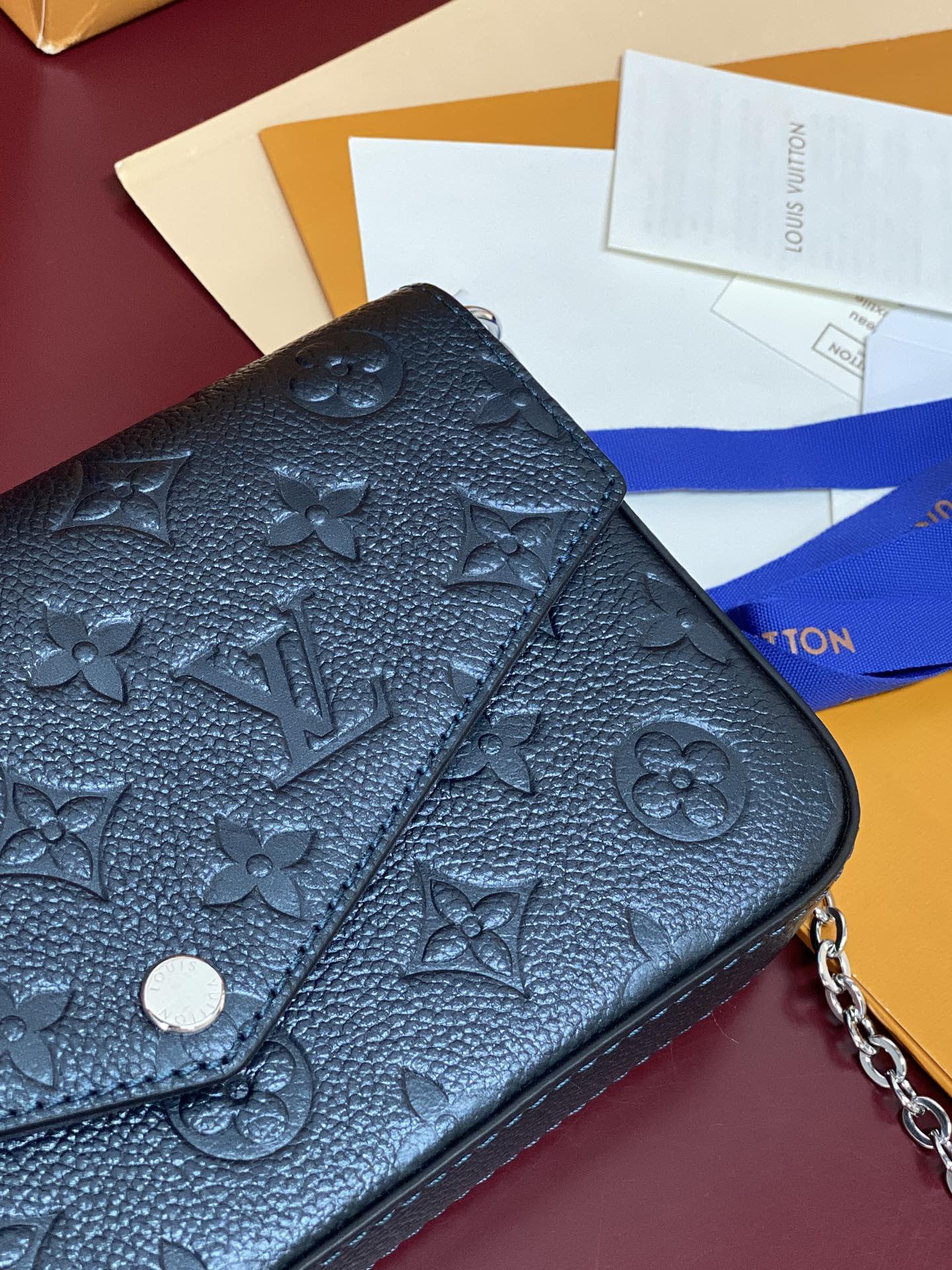 Blue embossed monogram flap bag close-up with snap button