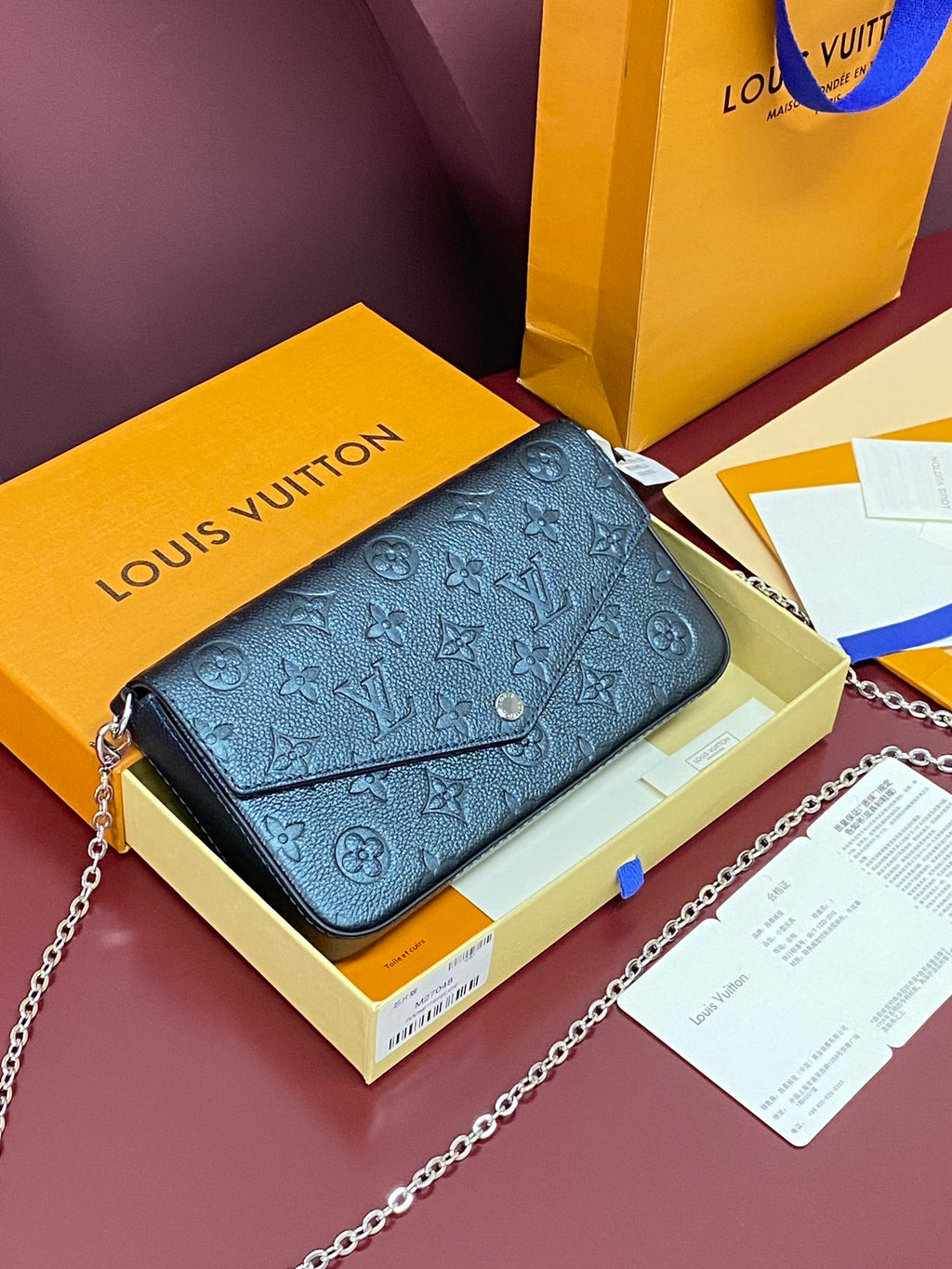 Blue monogram flap bag with chain strap, shown on its box and papers