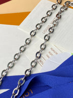 Silver chain straps on a blue monogram bag, with brand papers nearby