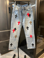 Light-wash denim pants with red and black cross patches, front view on hanger