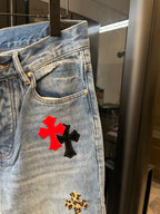 Light-wash denim pants front pocket with red cross patch and gold leopard cross