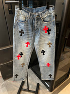 Light-wash denim pants with red, black, and gold cross patches, front view
