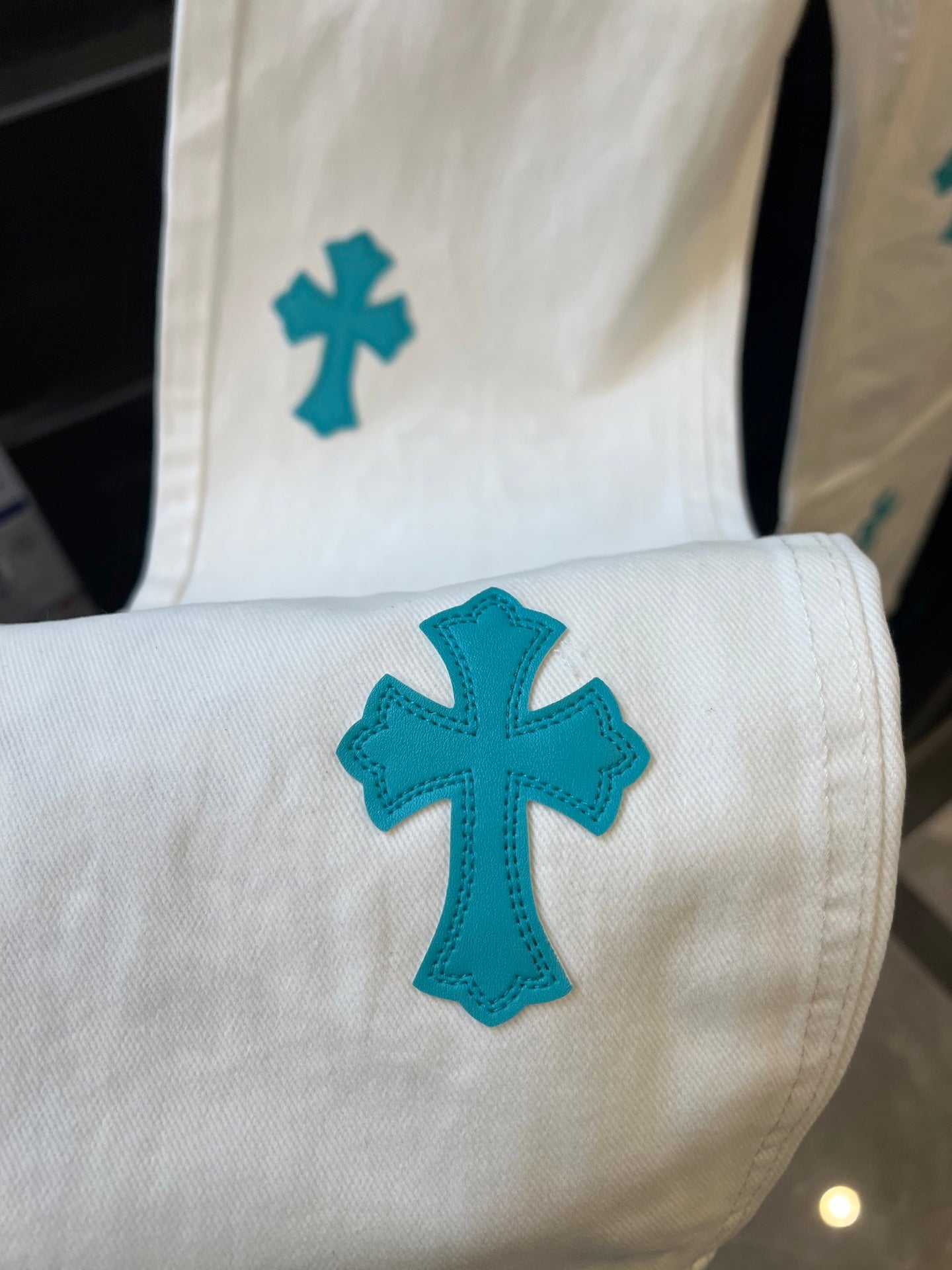 Chrome pants in white with large teal cross graphic on pocket area