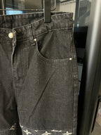 Dark denim jeans with front pockets and white monogram print at the hem edge