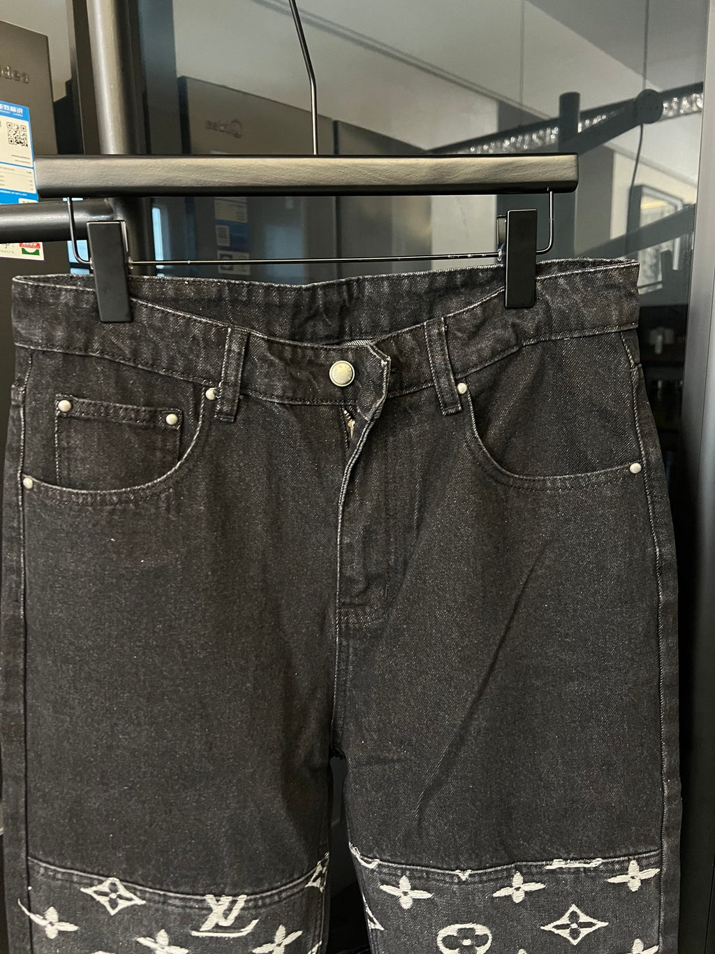 Dark denim jeans with front button, pocket stitching, and white monogram hem band