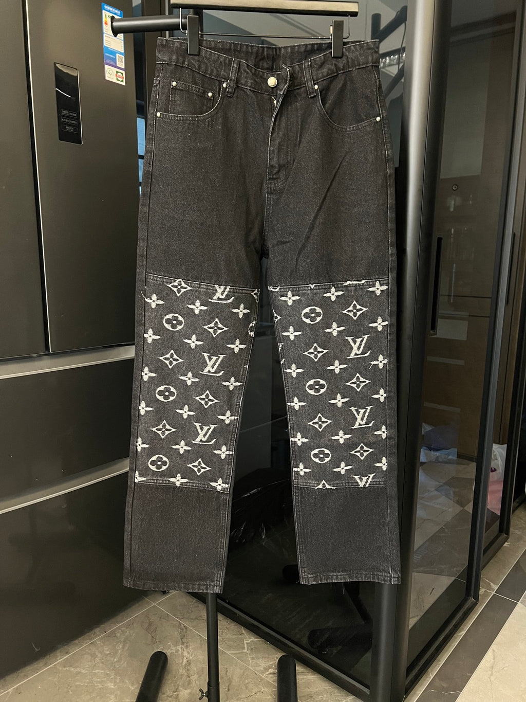 Dark denim pants with white monogram print band across the lower legs