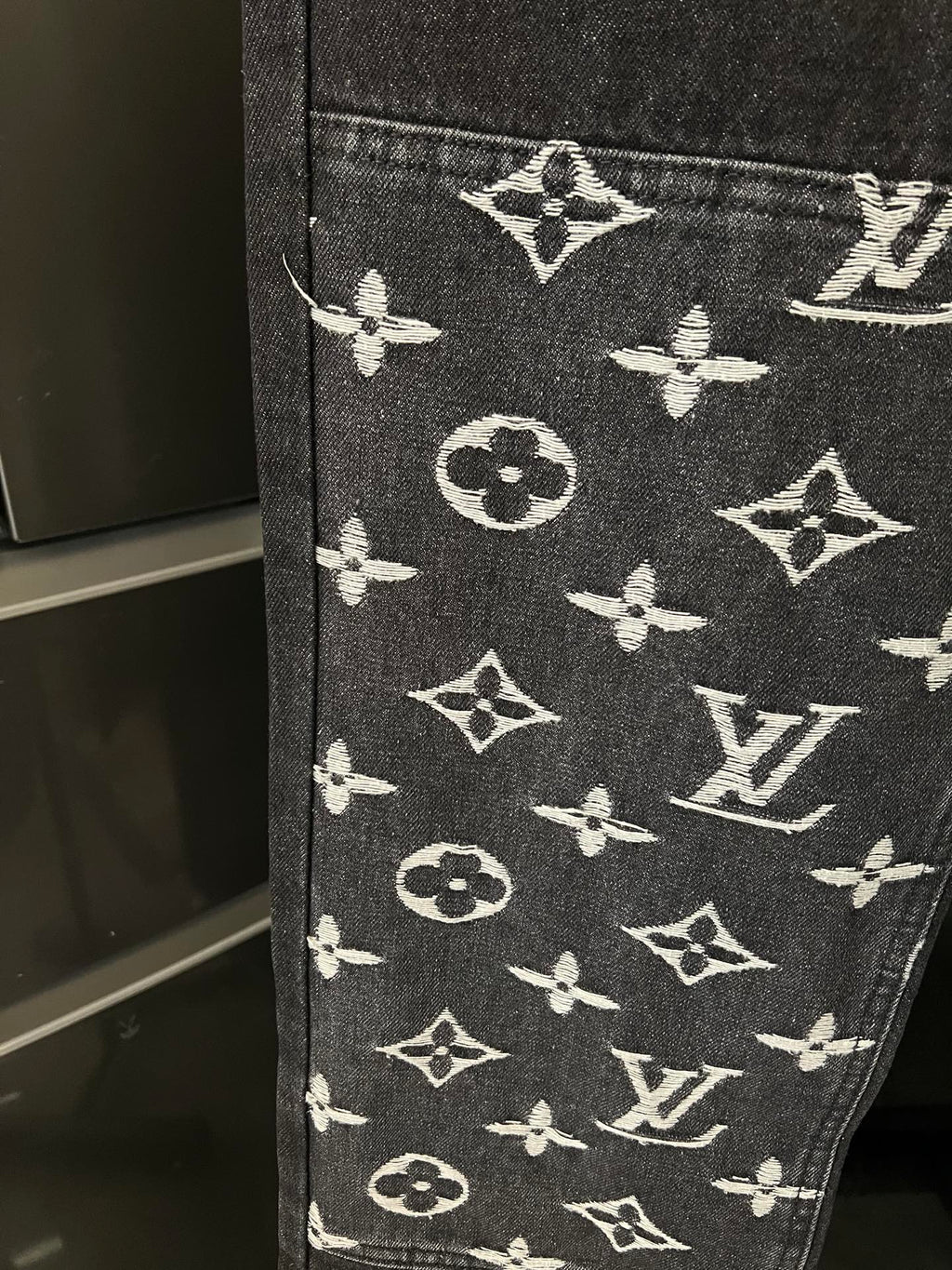 Dark denim fabric with white monogram pattern at the lower leg