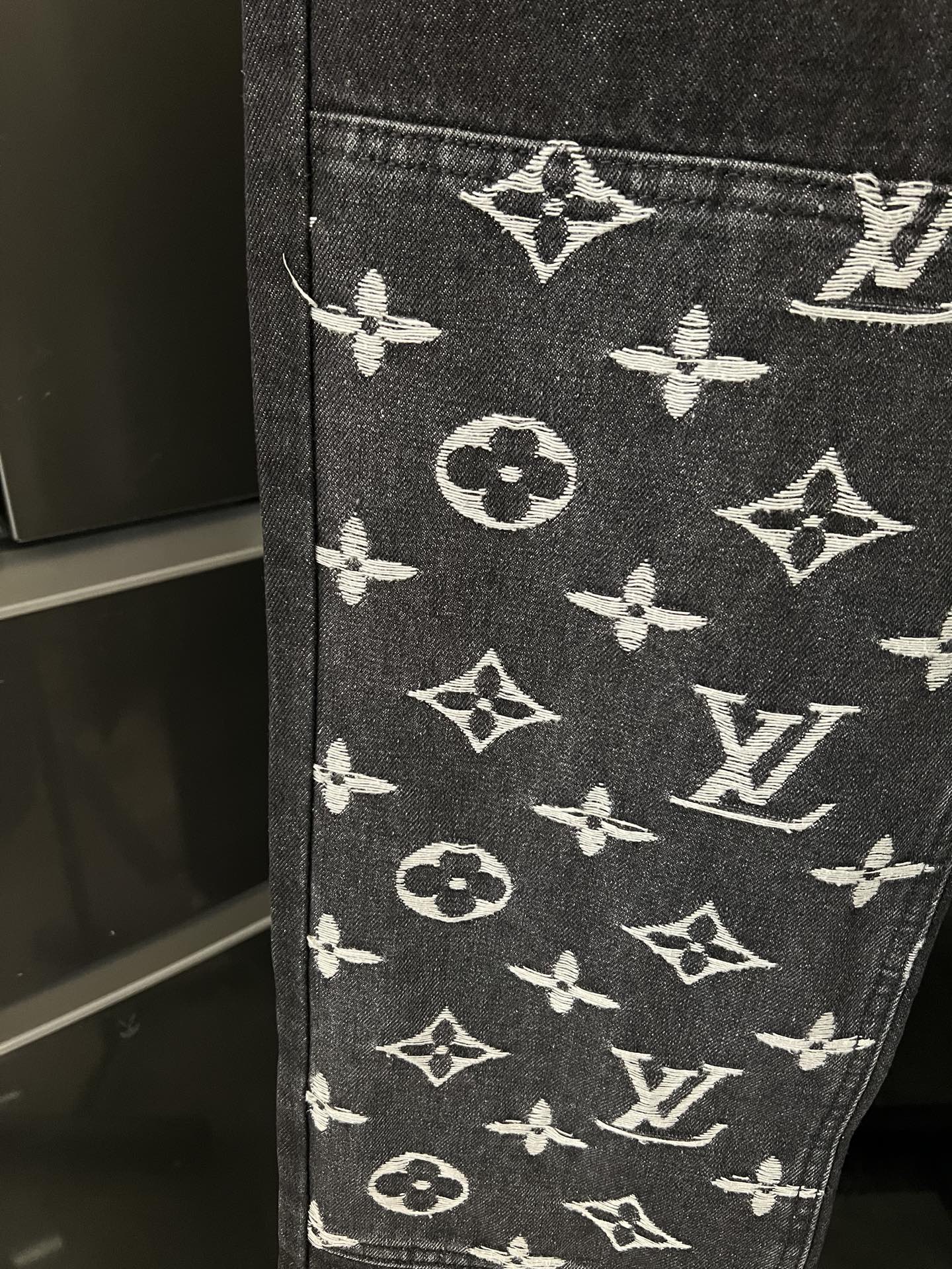 Dark denim fabric with white monogram pattern at the lower leg