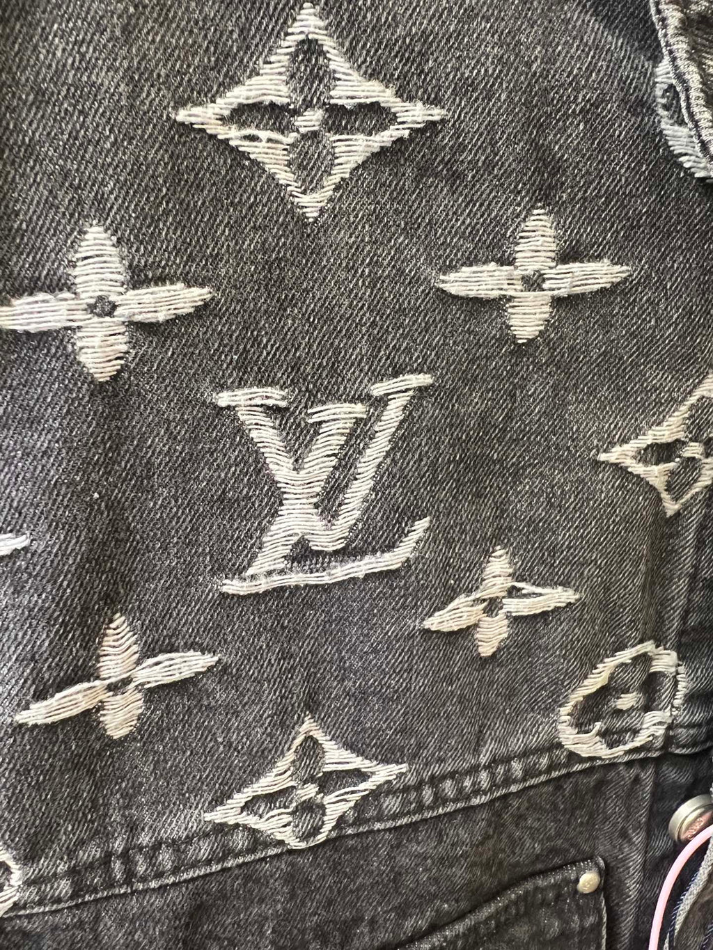 Close-up of denim jacket monogram pattern, dark gray with cream Louis Vuitton icons