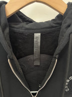 Black hoodie hood interior with brand label tag and front zipper teeth visible.