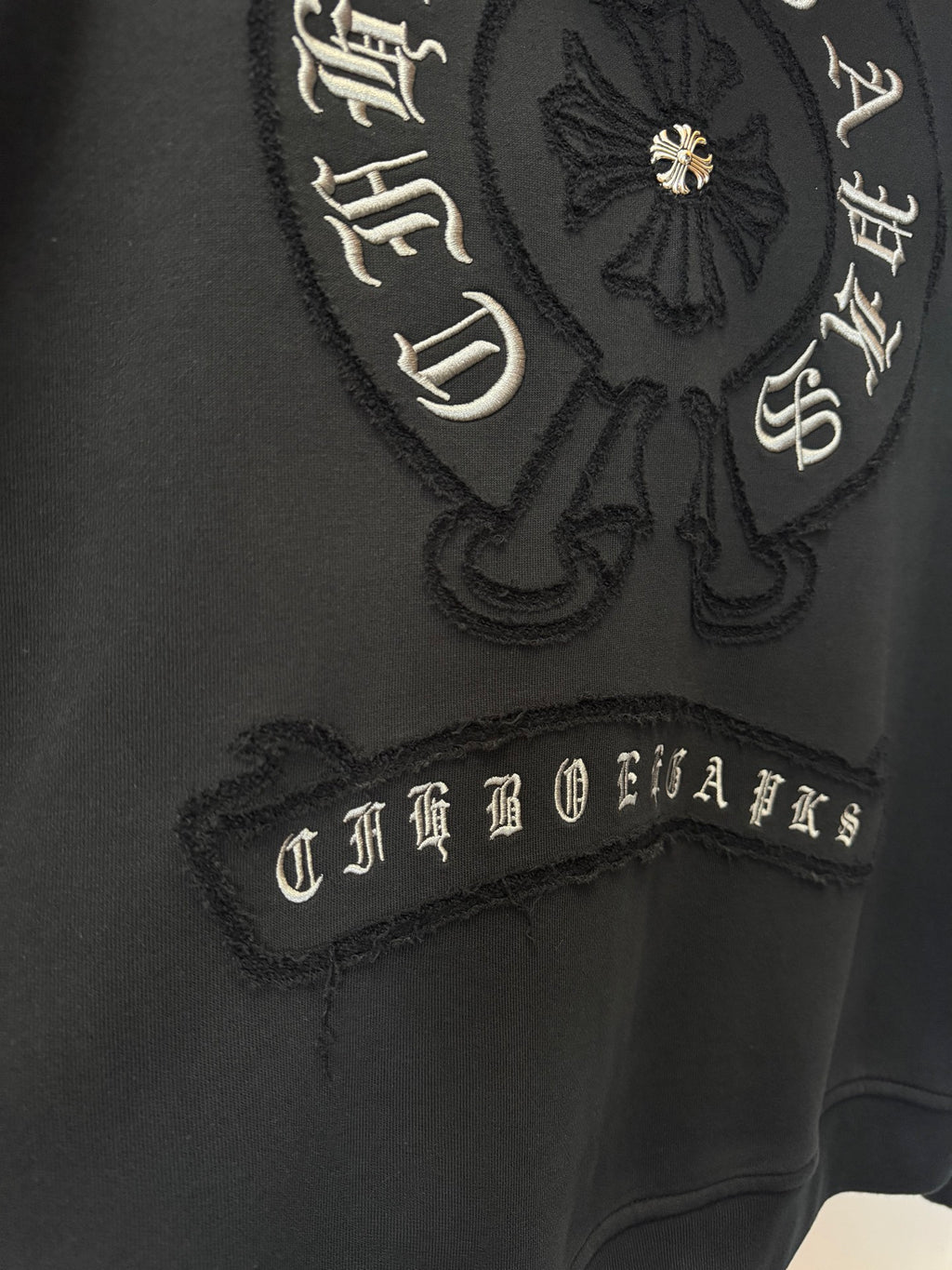 Black hoodie with embroidered crest and script lettering on the chest