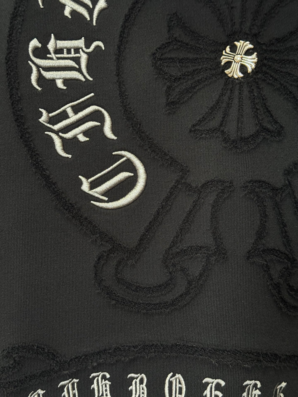 Black hoodie fabric with ornate emblem embroidery