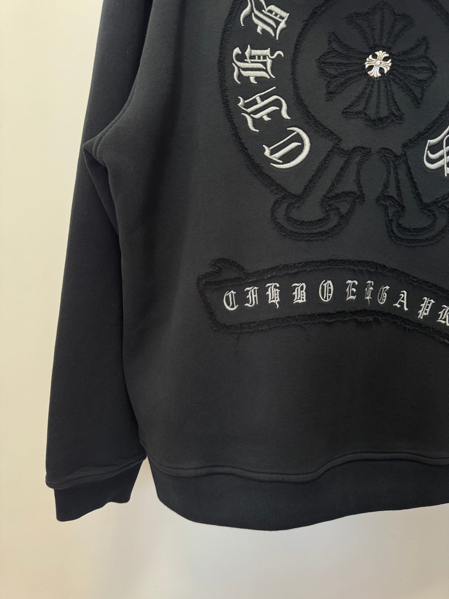 Black hoodie with embroidered crest, script trim, and kangaroo pocket