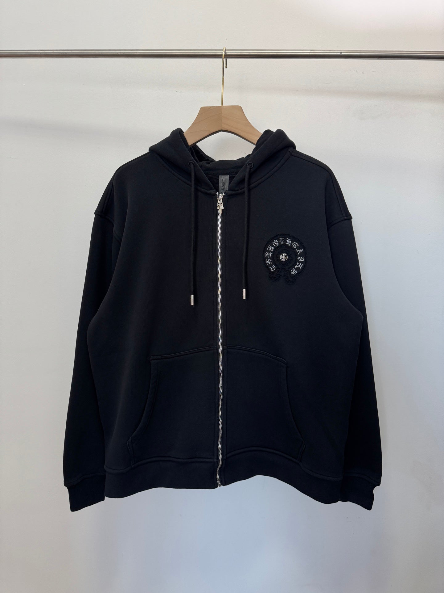 Black zip-up hoodie with hood, drawstrings, full front zipper, small chest emblem.