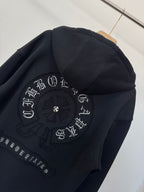 Black zip-up hoodie back detail with circular embroidery and decorative lettering.