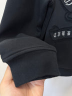 Black hoodie sleeve with ribbed cuff and embroidered chest detail