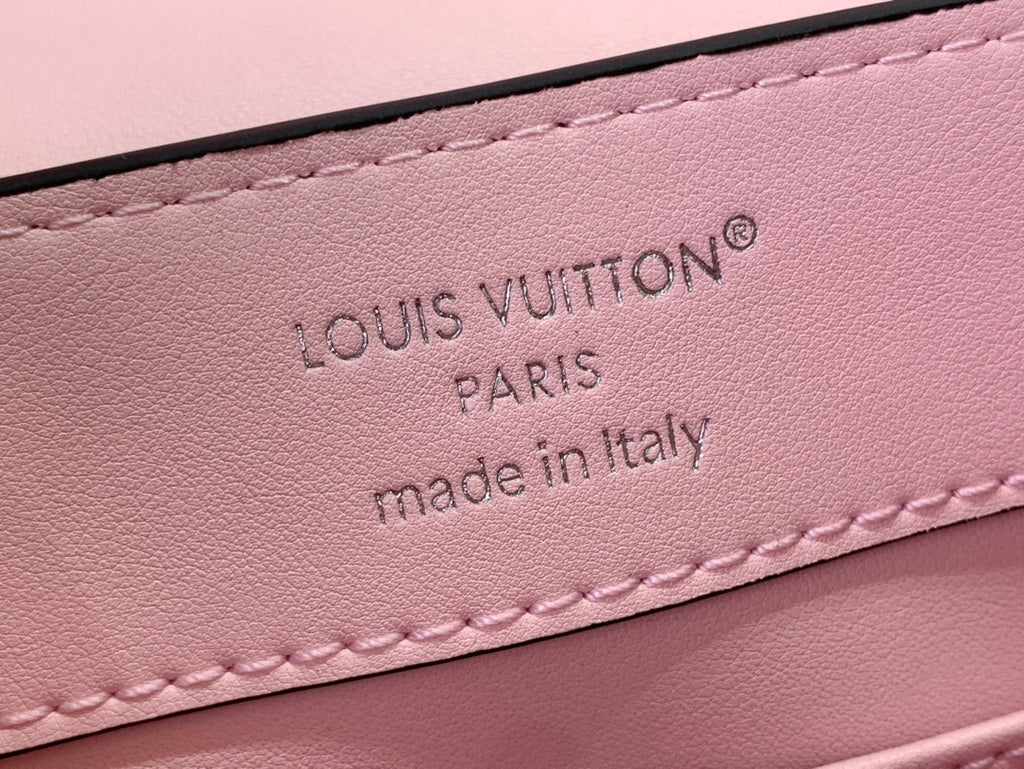 Louis Vuitton pink leather label area with embossed logo text and stitching