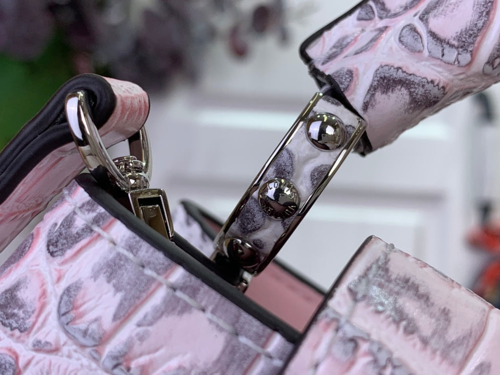Louis Vuitton handbag corner with glossy metal rings and pink croc-embossed trim