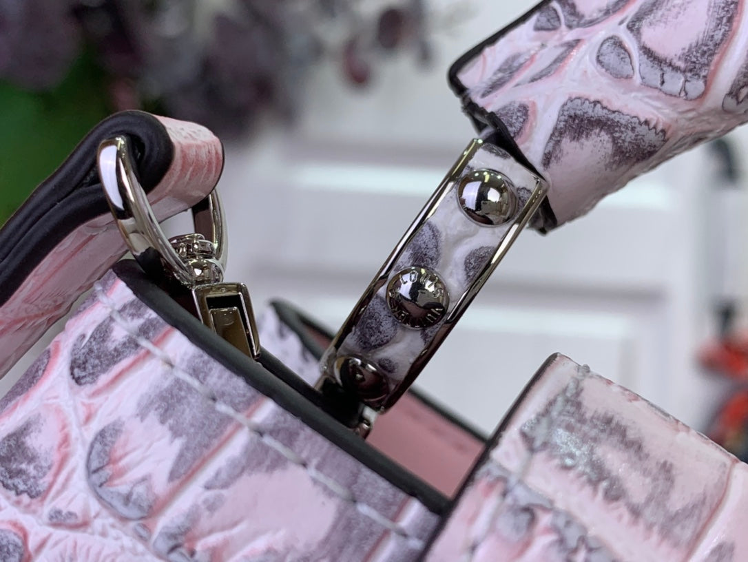 Louis Vuitton handbag corner with glossy metal rings and pink croc-embossed trim