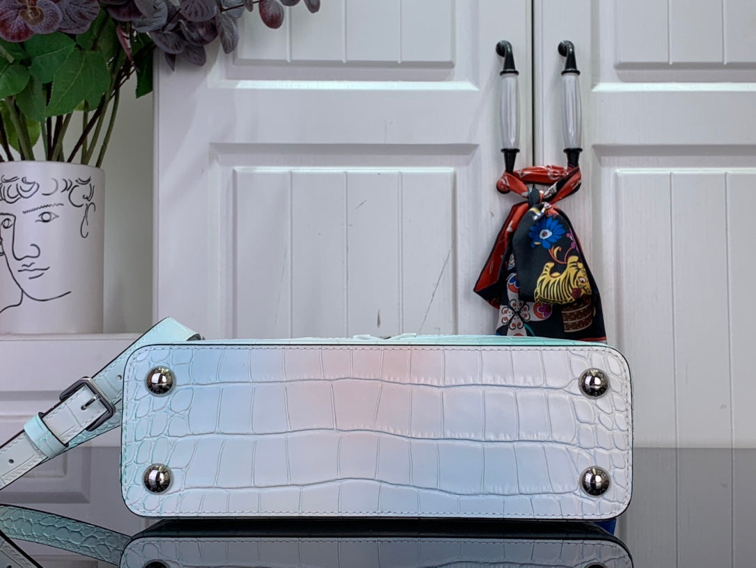 Light blue crocodile-embossed handbag with flap front, rivets, and shoulder strap