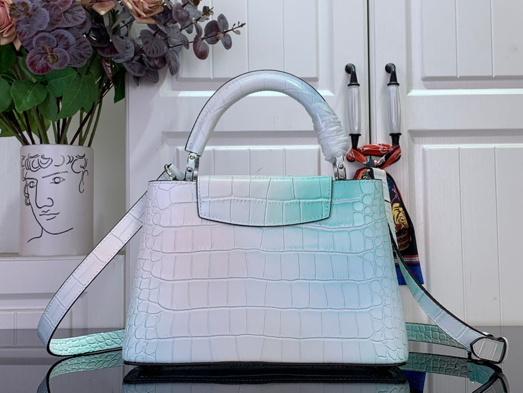 Light blue crocodile-embossed handbag with top handle and adjustable shoulder strap