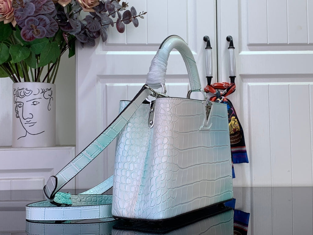 Light blue crocodile-embossed handbag with top handle and long shoulder strap