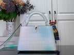 Light blue crocodile-embossed handbag with top handle and structured front panel